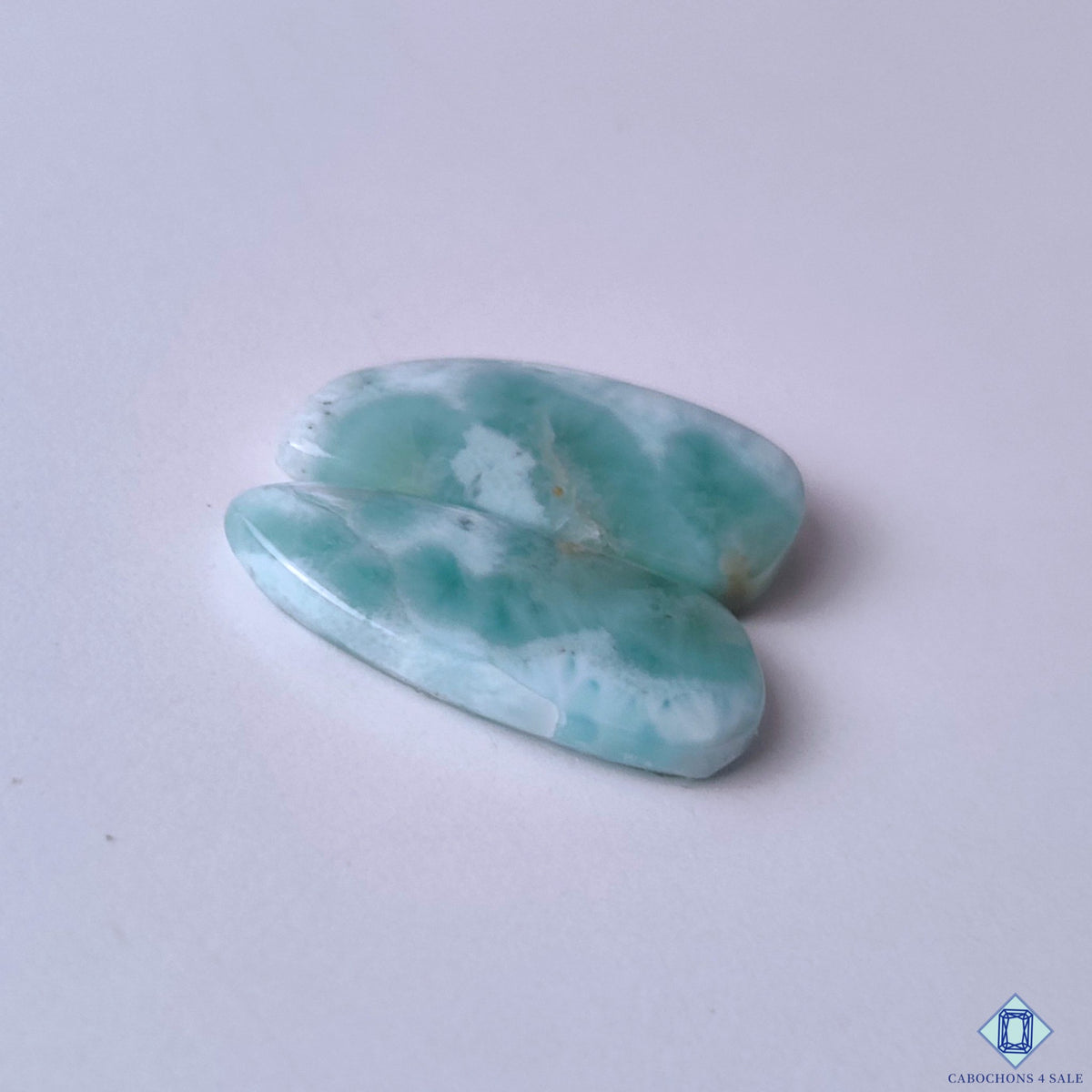 cabochons4sale, fancy blue and white larimar cabochons featuring tropical seascape-inspired markings, natural color variation and distinctive gemstone texture held between fingers