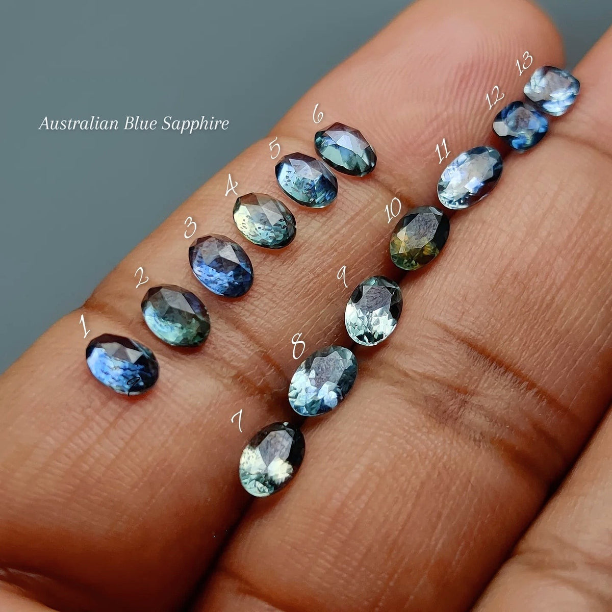Cabochons4sale natural faceted Australian blue sapphires in various shades held in a hand for scale.