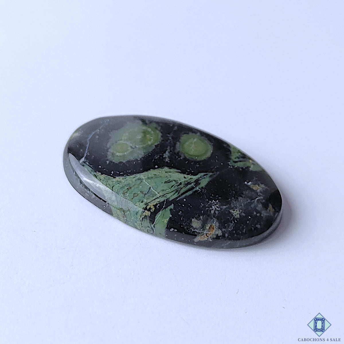 cabochons4sale, polished Kambaba Jasper oval cabochons showcasing deep green hues, contrasting black orb-like formations and unique natural stone character held between fingers