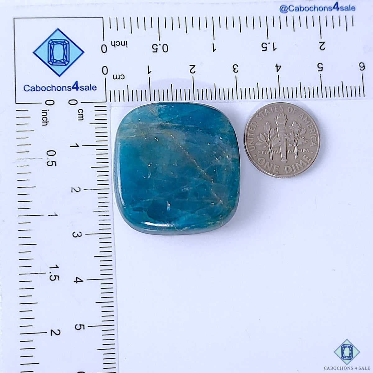 Cabochons4sale blue opaque apatite fancy cabochon gemstone measuring 30x28x6mm next to a US dime for scale.