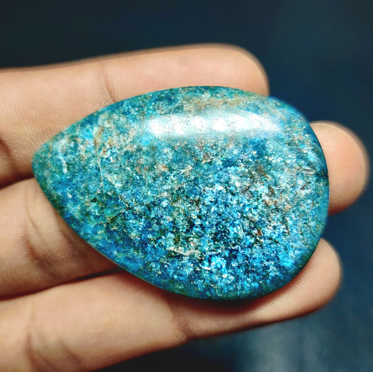 Cabochons4sale natural pear-shaped green apatite cabochon gemstone with a translucent finish held in a hand