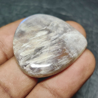 Cabochons4sale pear-shaped translucent white Belomorite cabochon gemstone held between fingers