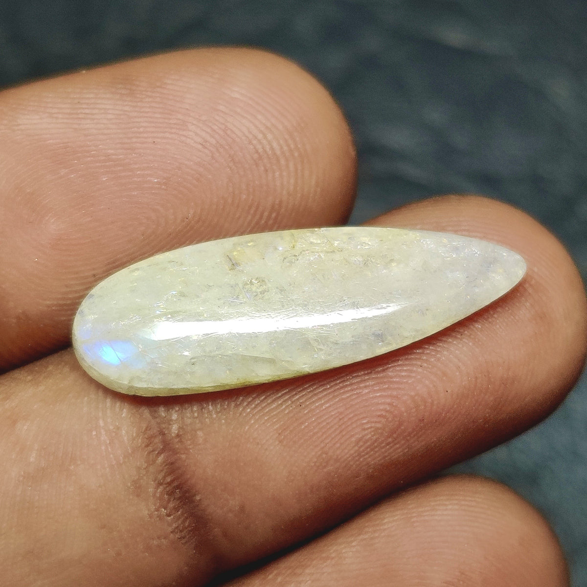 Cabochons4sale pear-shaped translucent white Belomorite gemstone cabochon held between fingers