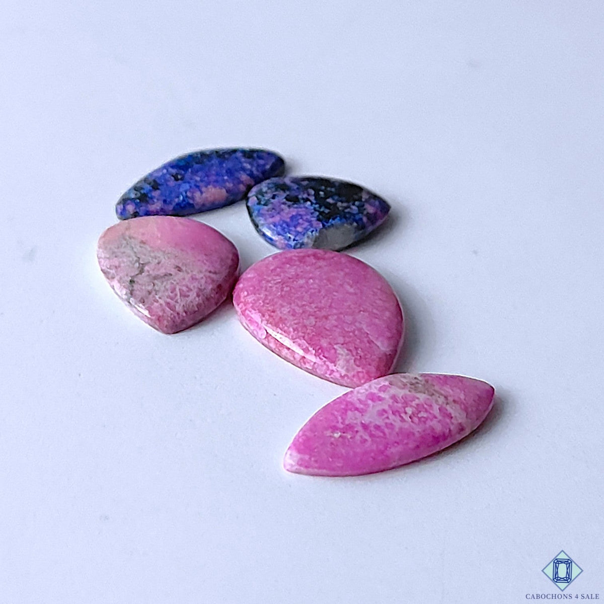 Cabochons4sale mix of opaque pink cobalt calcite and blue patterned gemstones in various shapes on white background