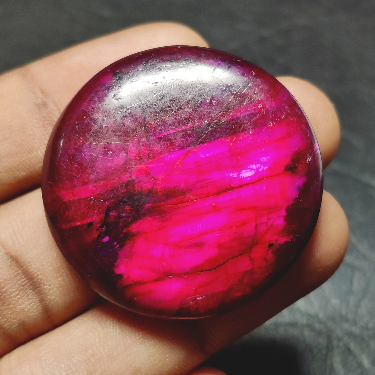 Cabochons4sale round purple dyed labradorite cabochon gemstone with translucent clarity held in a hand
