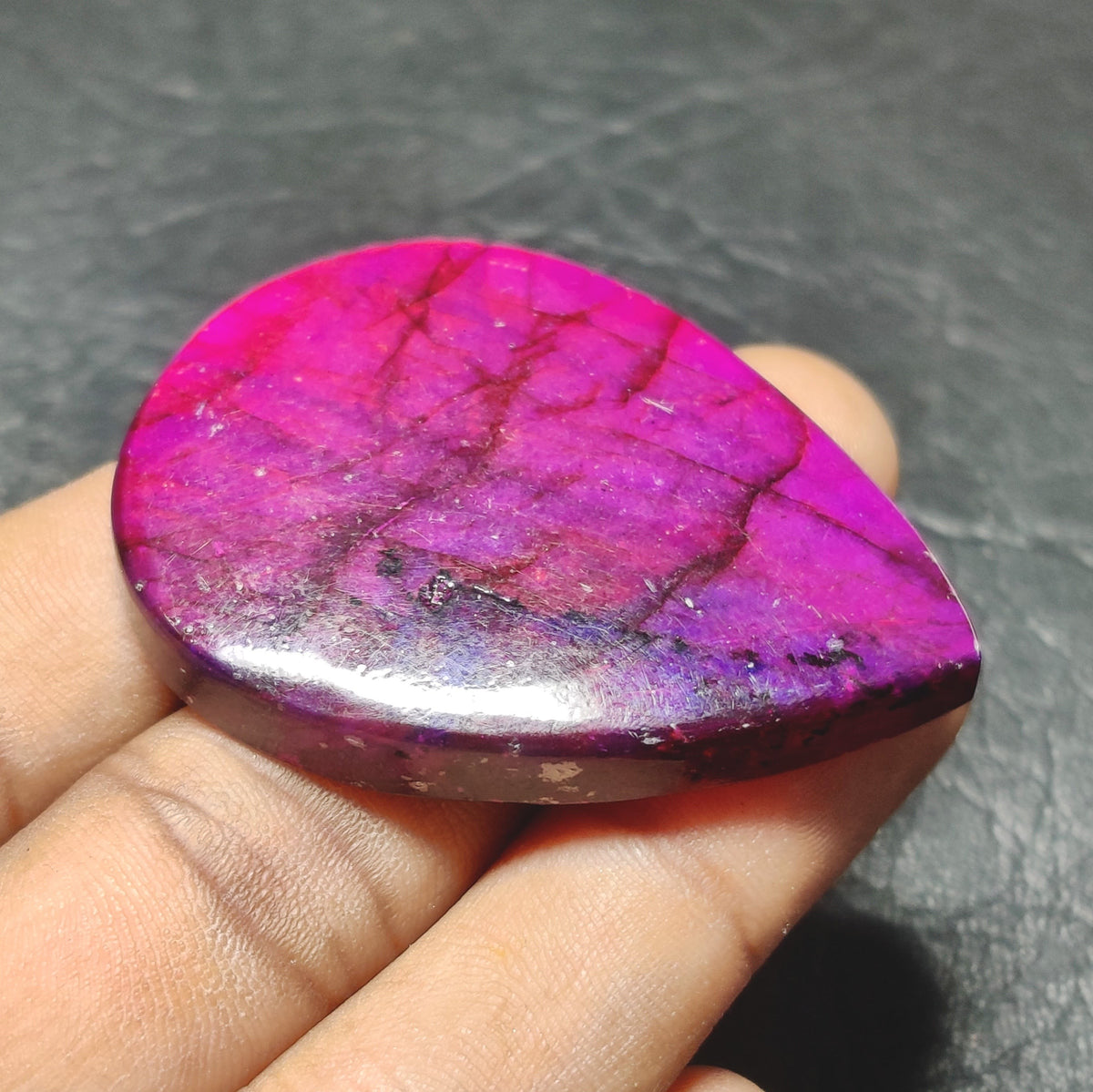 Cabochons4sale purple dyed labradorite pear cabochon gemstone with translucent finish held in hand