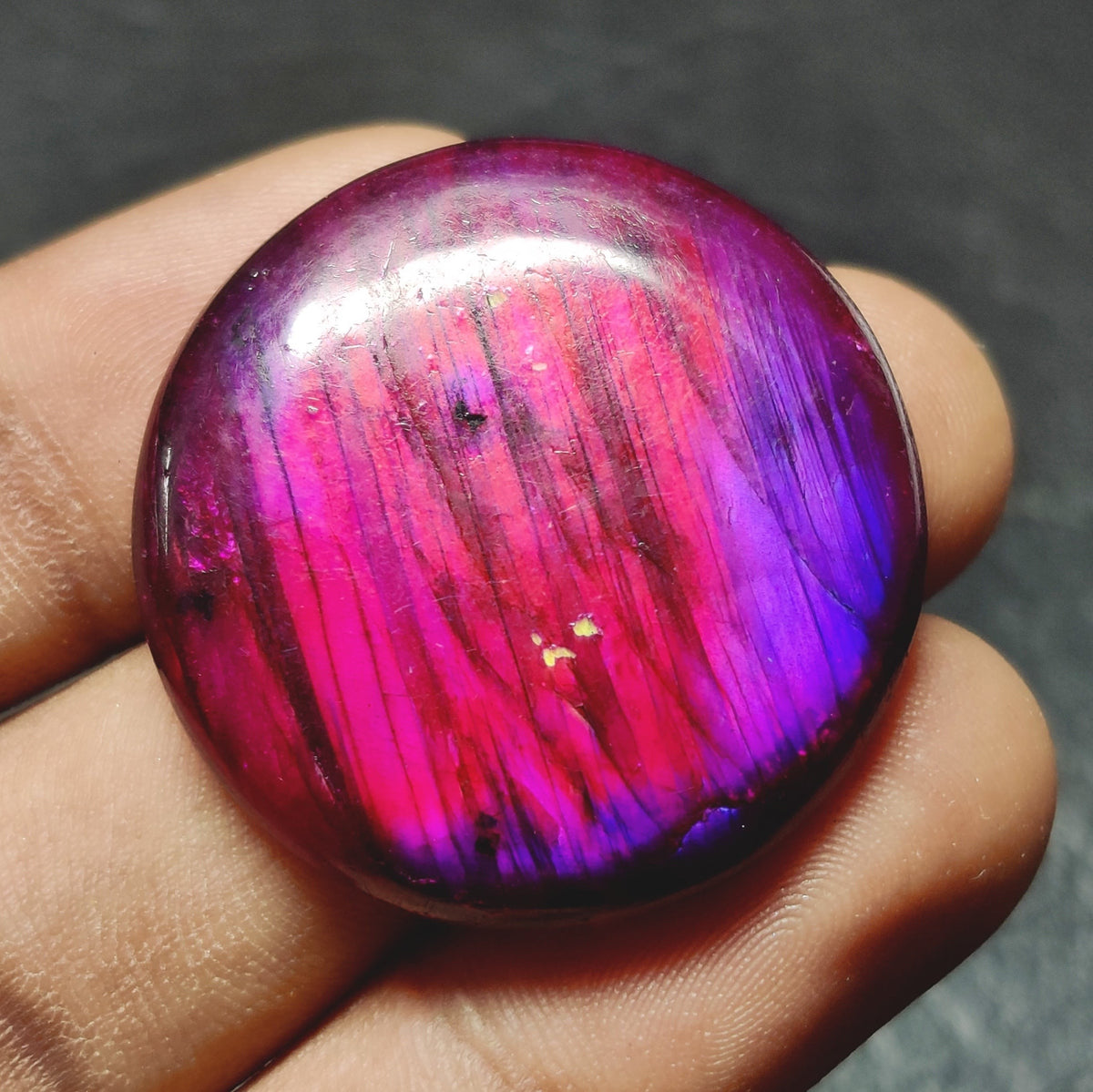 Cabochons4sale round purple dyed labradorite cabochon gemstone with translucent finish held in hand