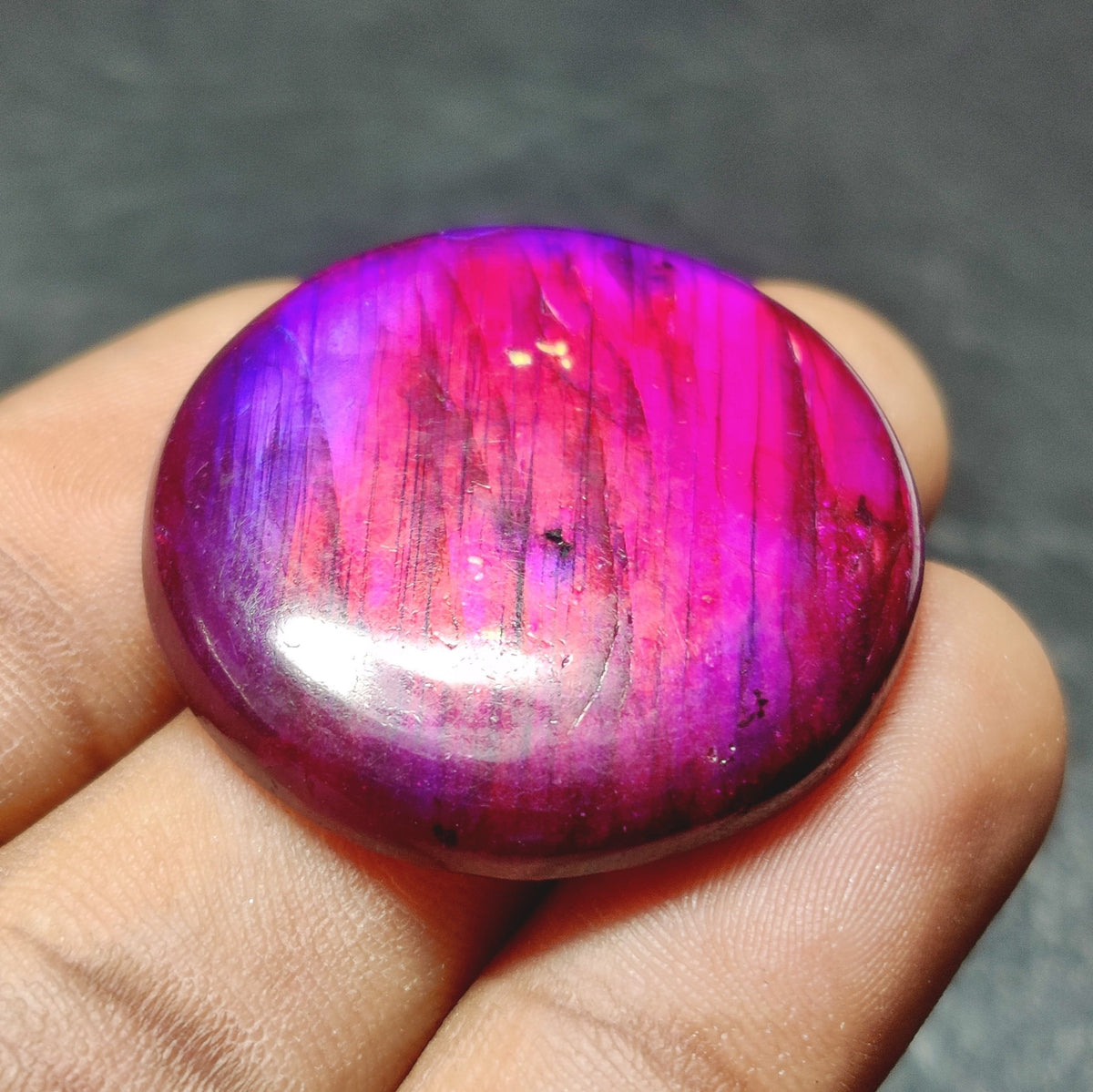 Cabochons4sale round purple dyed labradorite cabochon gemstone with translucent finish held in fingers