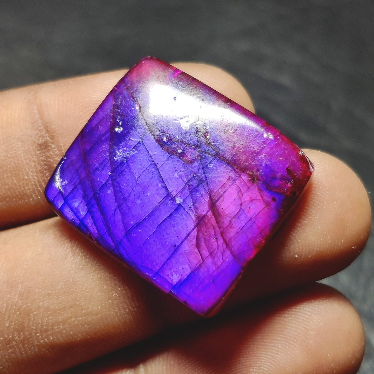 Cabochons4sale square purple dyed labradorite cabochon gemstone with translucent finish held between fingers