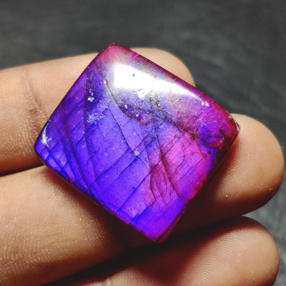 Cabochons4sale square purple dyed labradorite cabochon gemstone with translucent finish held between fingers