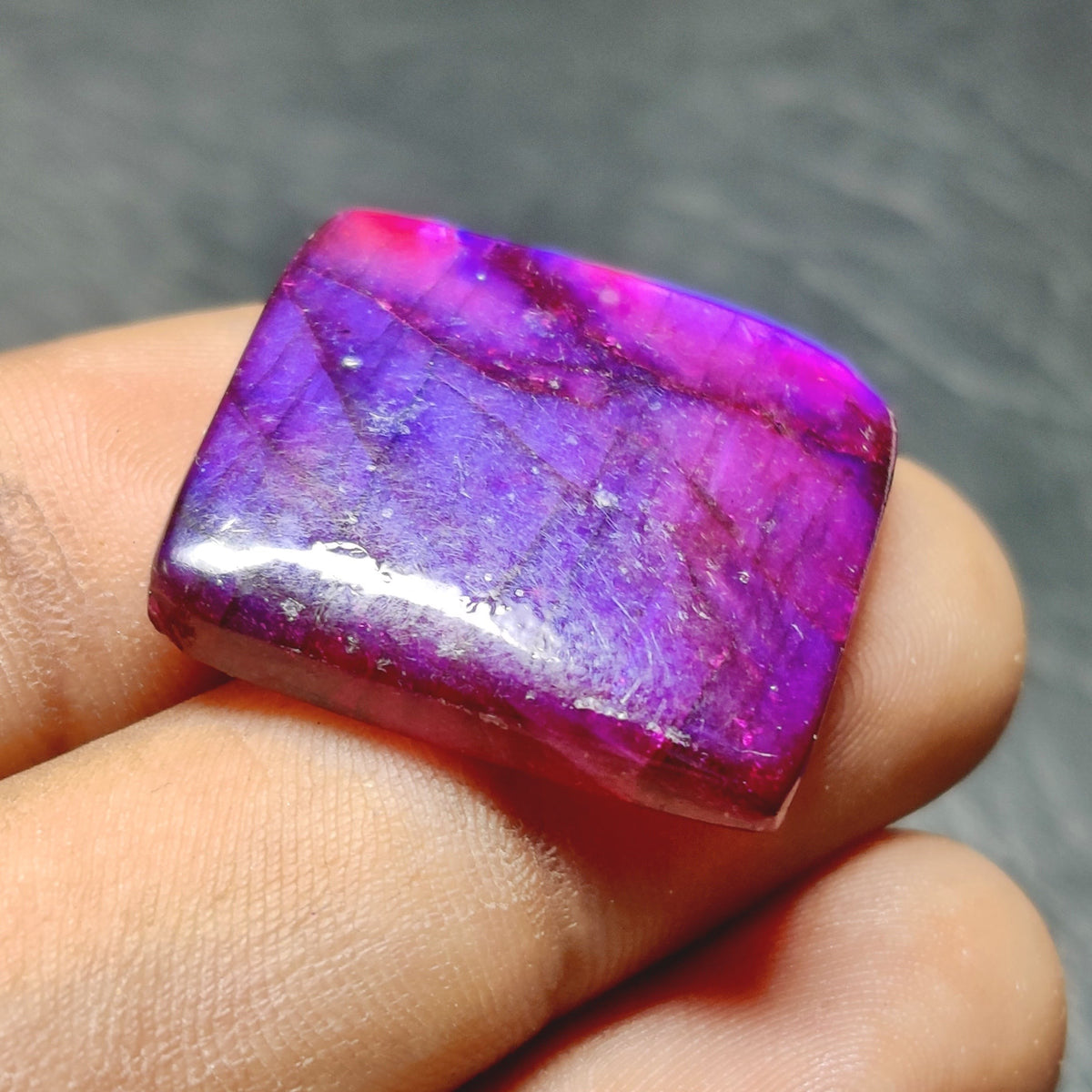 Cabochons4sale square purple dyed labradorite gemstone cabochon with translucent finish held between fingers