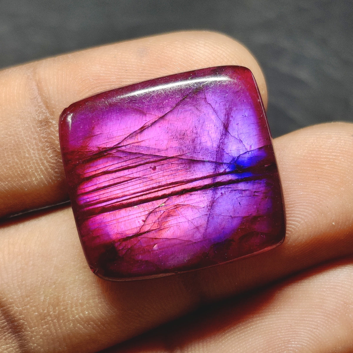 Cabochons4sale square purple dyed labradorite cabochon with translucent finish held in fingers