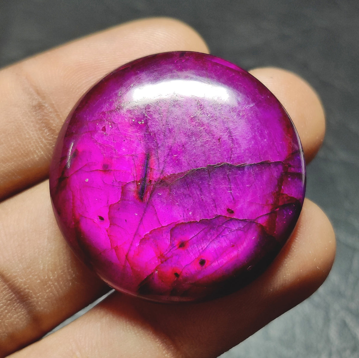 Cabochons4sale round purple dyed labradorite cabochon gemstone with translucent finish held in hand