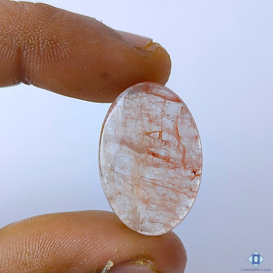 Cabochons4sale oval Fire Quartz cabochon with red inclusions in a translucent gemstone held between fingers