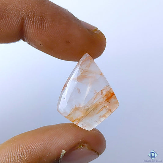 Cabochons4sale translucent fire quartz fancy cabochon with red inclusions held between fingers