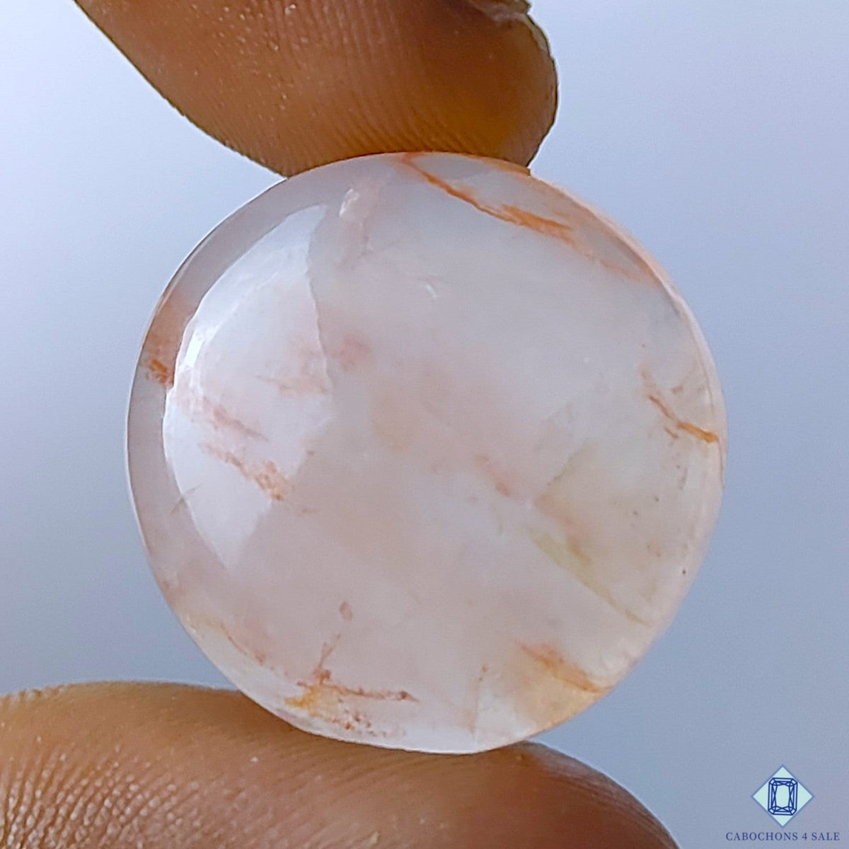 Cabochons4sale round translucent fire quartz cabochon with red inclusions held between fingers
