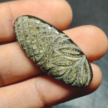 Cabochons4sale oval golden obsidian gemstone with intricate leaf and grid carving, translucent yellow-gold finish.