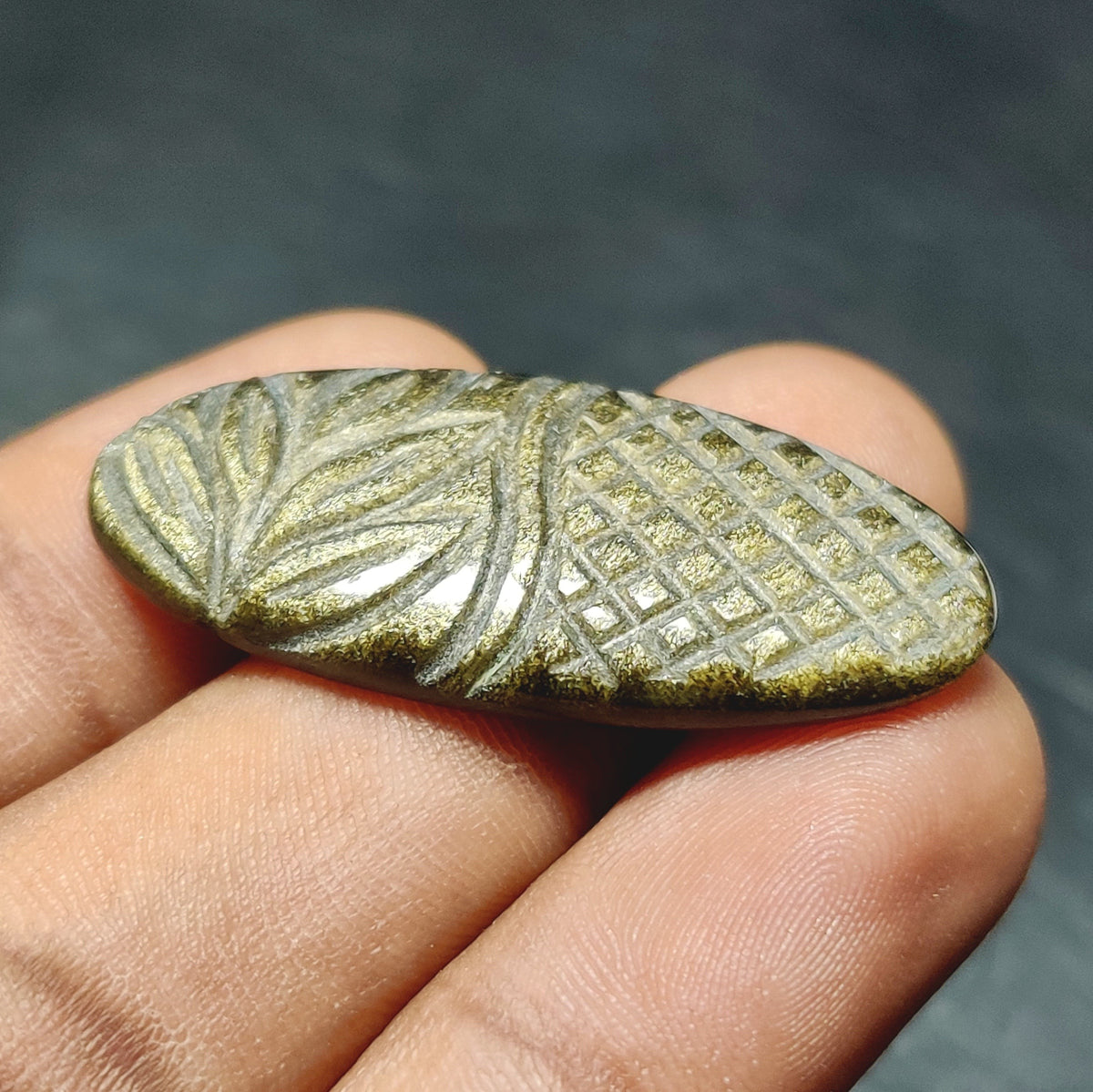 Cabochons4sale oval golden obsidian gemstone with intricate leaf and grid carvings in a translucent yellow hue.