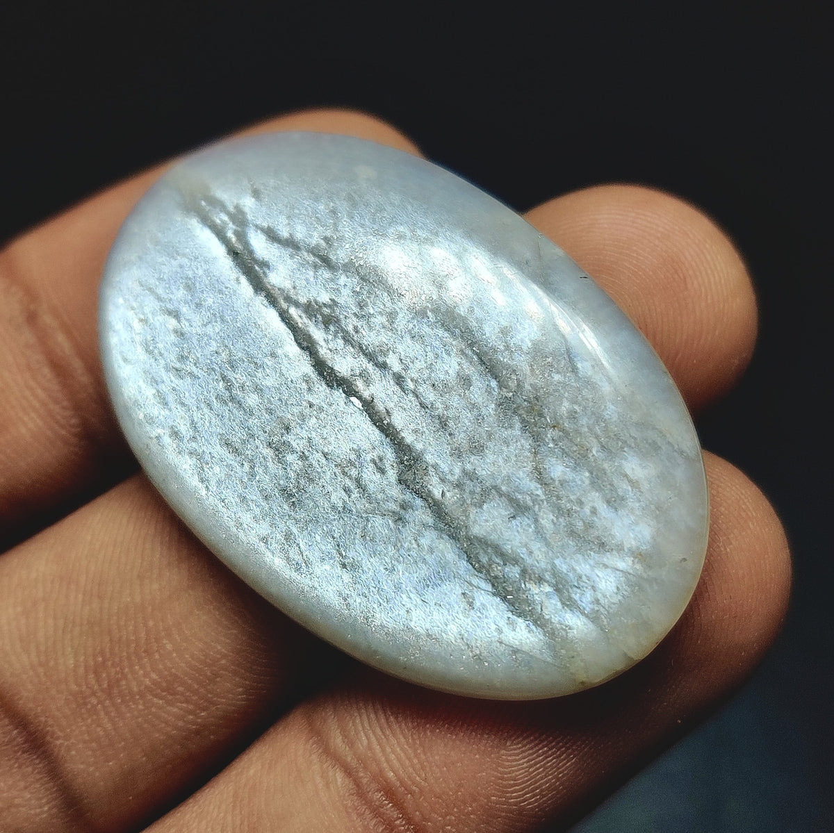 Cabochons4sale oval grey moonstone cabochon with a translucent finish held in a hand
