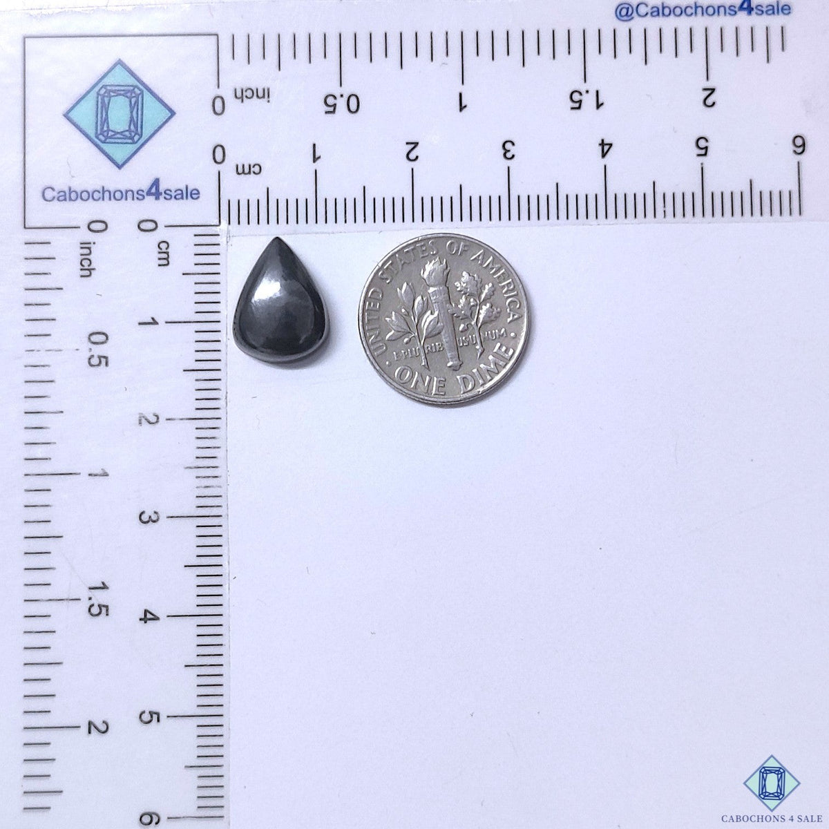 Cabochons4sale grey gun metal pear cabochon gemstone measuring 13x10x4mm next to a US dime for scale.