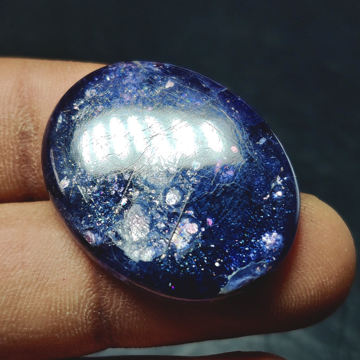 Cabochons4sale oval translucent blue iolite cabochon gemstone held between fingers showing natural inclusions