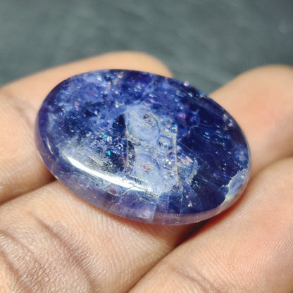 Cabochons4sale oval blue iolite gemstone cabochon with a translucent finish held in a hand