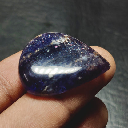 Cabochons4sale pear-shaped translucent blue iolite cabochon gemstone held between fingers
