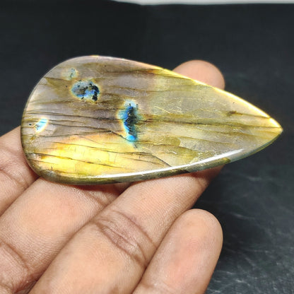 Cabochons4sale pear-shaped yellow labradorite cabochon with translucent finish held in a hand