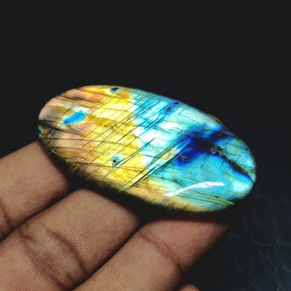 Cabochons4sale oval labradorite cabochon with vibrant blue and yellow iridescent flashes held in a hand