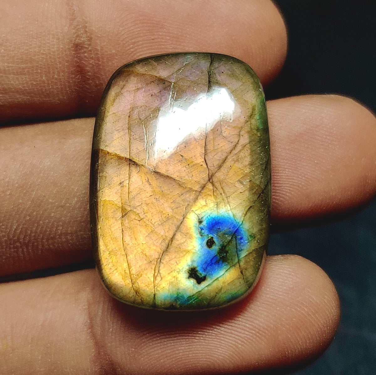 Cabochons4sale rectangular labradorite cabochon with translucent multi-colour flashes held between fingers