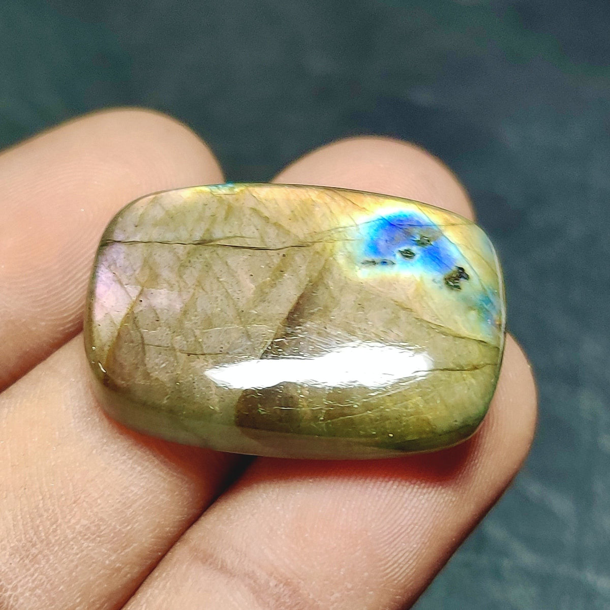 Cabochons4sale rectangular labradorite cabochon with translucent multi-colour flash held between fingers