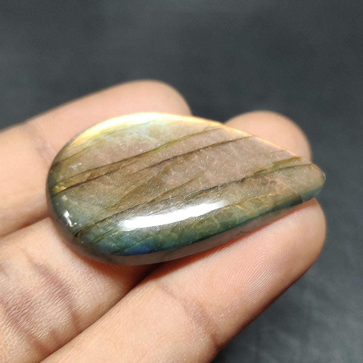 Cabochons4sale pear-shaped labradorite cabochon with translucent multi-colour iridescent flashes held in a hand.
