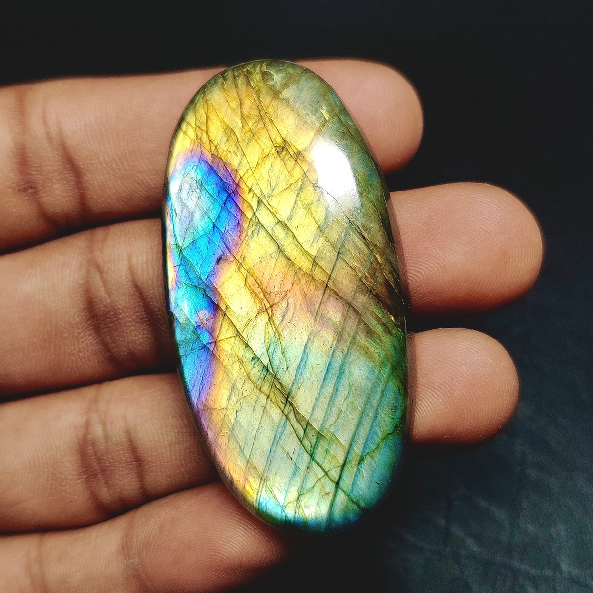 Cabochons4sale oval labradorite cabochon with vibrant blue and yellow iridescent flash held in a hand