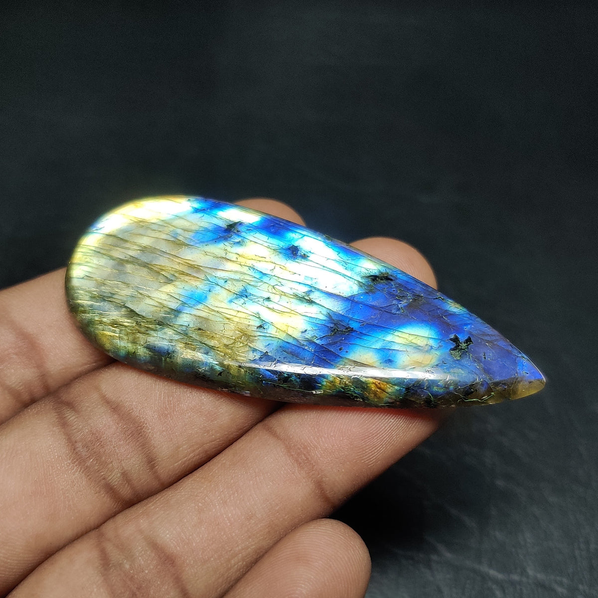 Cabochons4sale pear-shaped labradorite cabochon with vibrant blue and yellow iridescent flash held in a hand