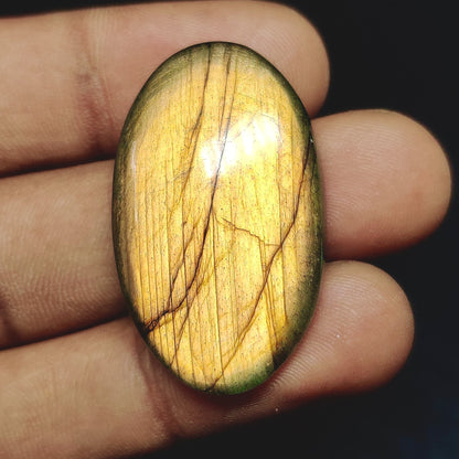 Cabochons4sale oval yellow labradorite cabochon gemstone with translucent clarity held in fingers