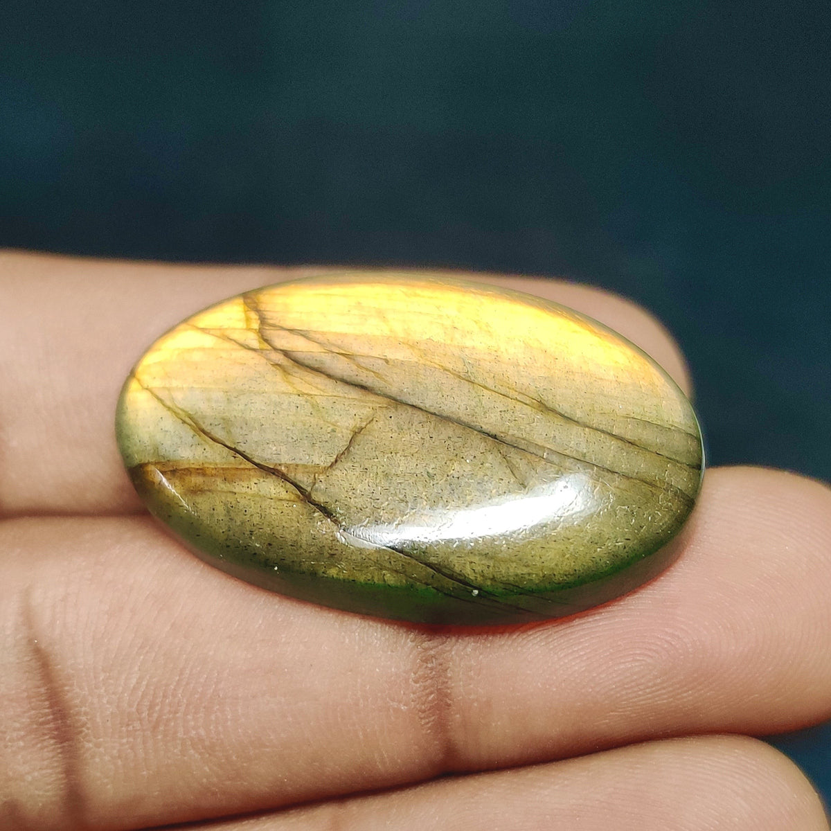 Cabochons4sale oval translucent yellow labradorite gemstone cabochon held between fingers