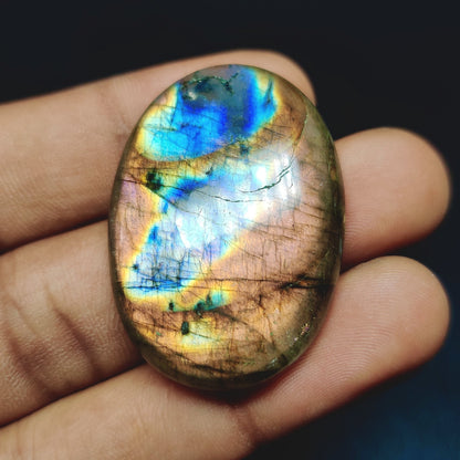 Cabochons4sale oval labradorite cabochon with vibrant blue and gold iridescent flashes held in a hand
