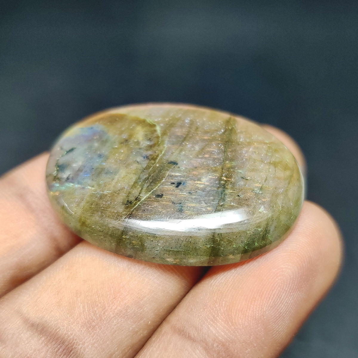 Cabochons4sale natural oval labradorite cabochon featuring translucent multi-colour tones held in a hand