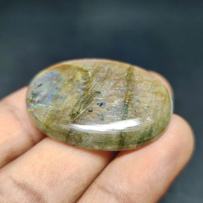 Cabochons4sale natural oval labradorite cabochon featuring translucent multi-colour tones held in a hand