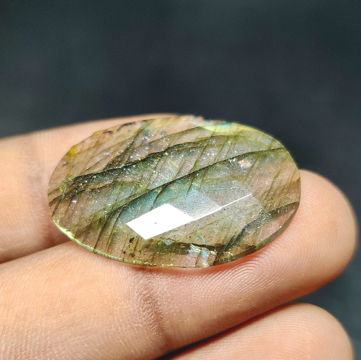 Cabochons4sale oval rose cut labradorite gemstone with translucent multi-colour flashes held between fingers