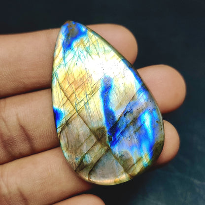 Cabochons4sale pear-shaped labradorite gemstone with iridescent blue and gold flashes held in a hand