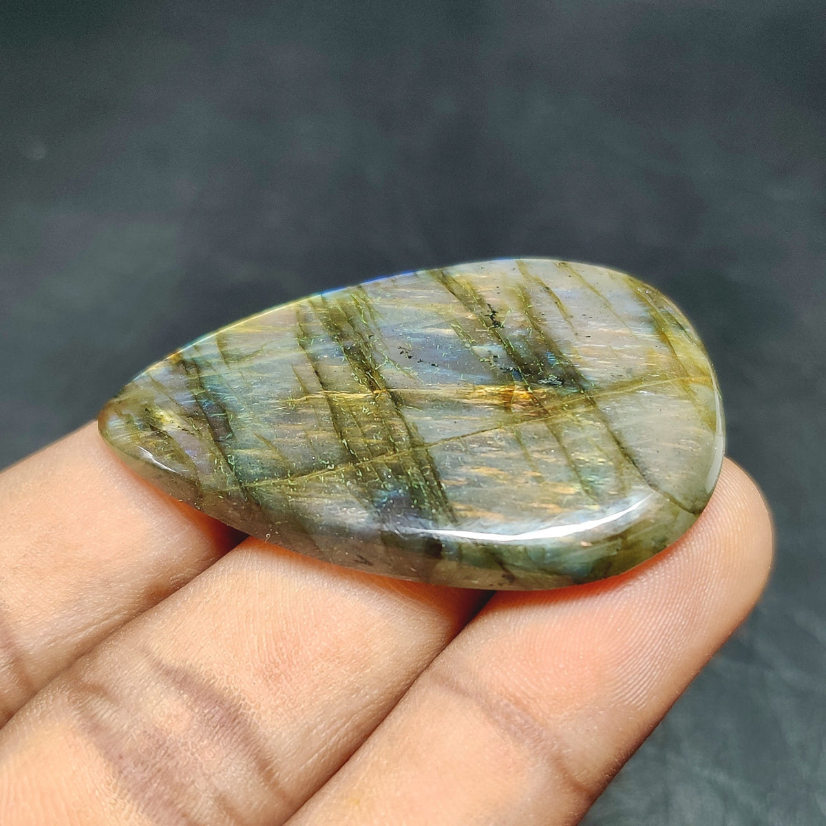 Cabochons4sale translucent pear-shaped labradorite gemstone with iridescent multi-colour flashes held in hand