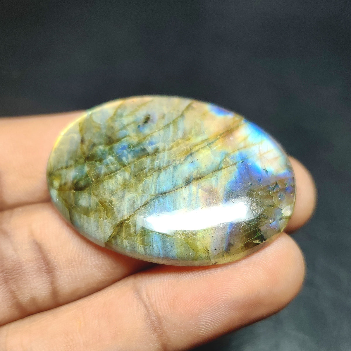 Cabochons4sale oval labradorite cabochon with translucent multi-colour iridescent flash held in hand