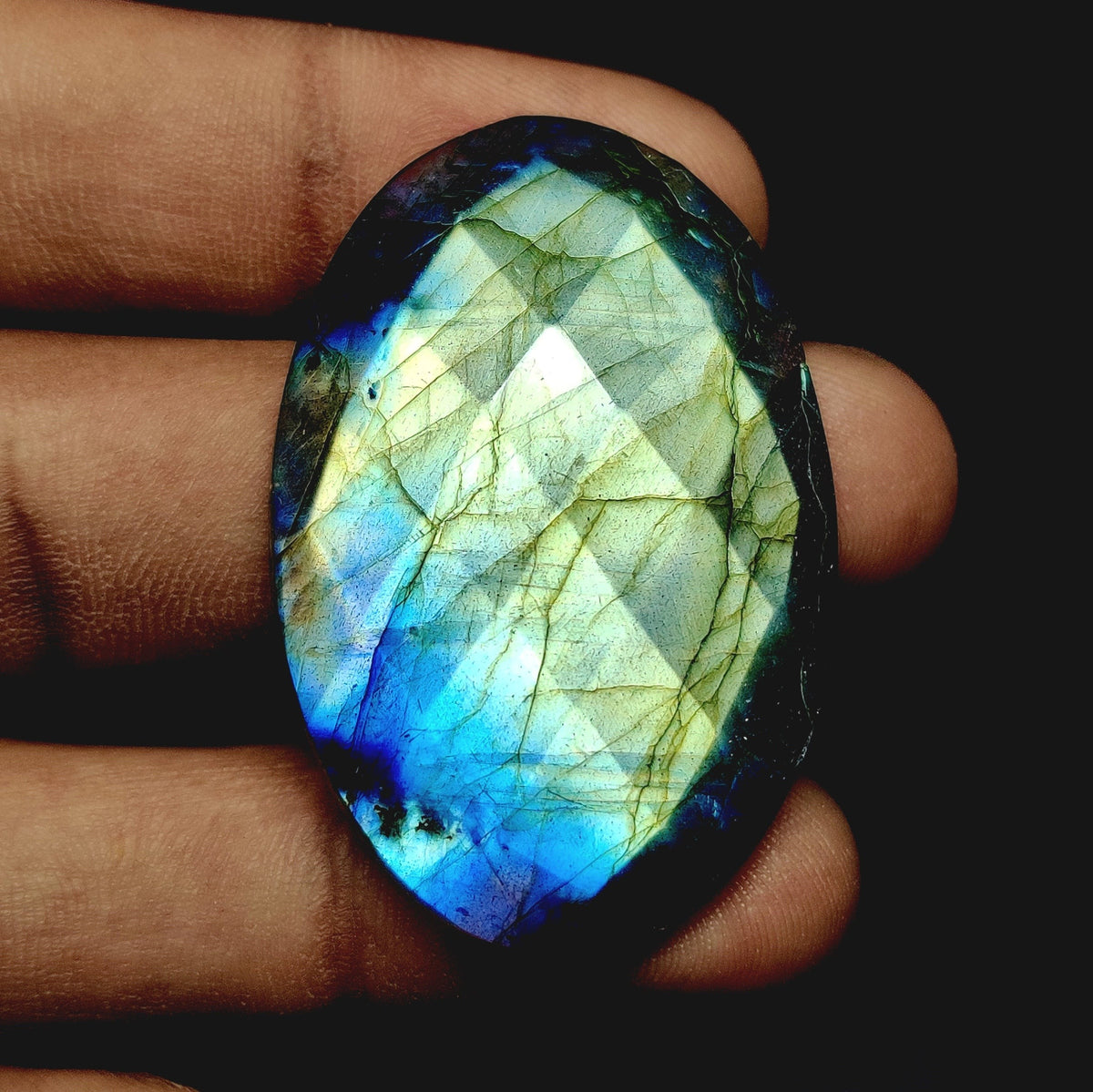 Cabochons4sale oval rose cut labradorite gemstone with iridescent blue and yellow flashes held in a hand