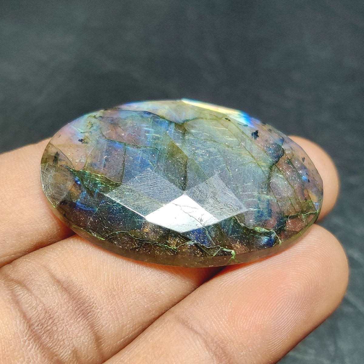 Cabochons4sale oval rose cut labradorite gemstone with translucent multi-colour flashes held in a hand
