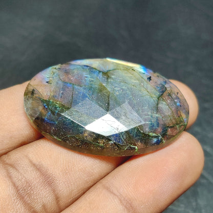 Cabochons4sale oval rose cut labradorite gemstone with translucent multi-colour flashes held in a hand