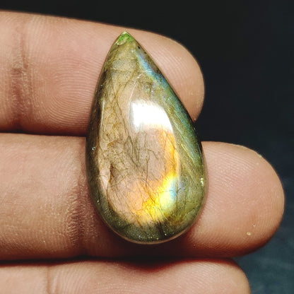 Cabochons4sale pear-shaped translucent labradorite gemstone with iridescent multi-colour flashes held in fingers