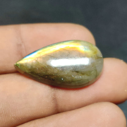 Cabochons4sale pear-shaped labradorite gemstone with translucent multi-colour iridescent flash held in hand