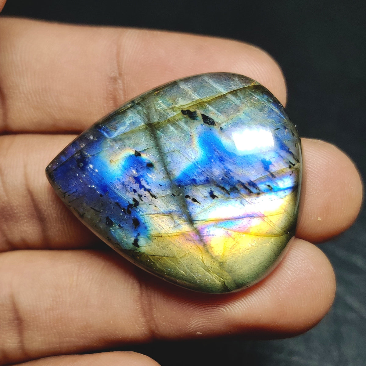 Cabochons4sale pear-shaped labradorite gemstone with translucent multi-colour iridescence held in a hand