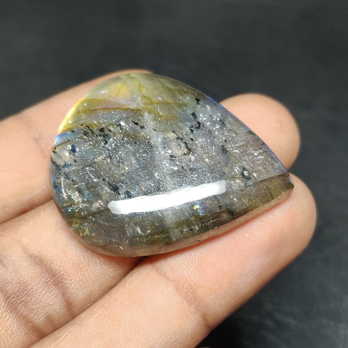 Cabochons4sale pear-shaped translucent labradorite gemstone with multi-colour iridescent flashes held in a hand.